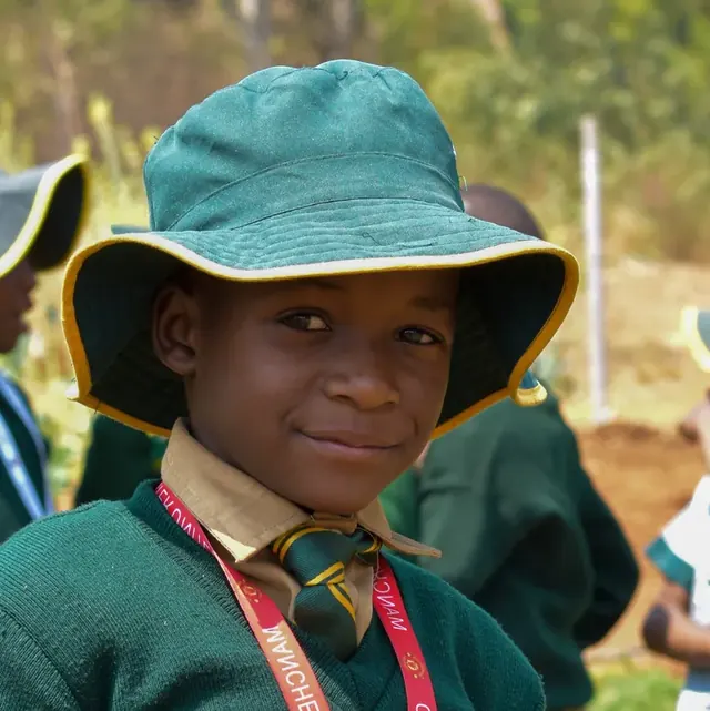 A smiling learner in the green school bush hat